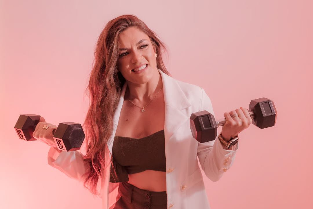 Amanda Sousa sorrindo, segurando dois halteres